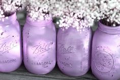 purple mason jars with baby's breath in them are lined up on a shelf