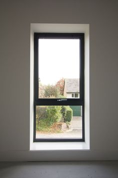 an empty room with a large window in the center and white walls on both sides