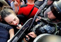 a group of people standing around each other in front of a police officer talking on a cell phone