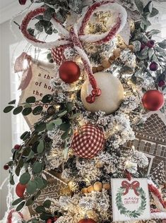 a decorated christmas tree with red and white ornaments on it's branches, bows, and ribbons