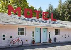 a motel with a bicycle parked in front of it and the word motel painted on top