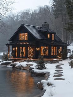 a house is lit up with christmas lights by the water