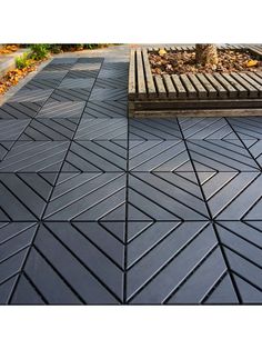 an outdoor patio with black tiles on the ground and trees in the backround