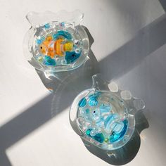 two clear bowls filled with different types of toy animals on top of a white surface