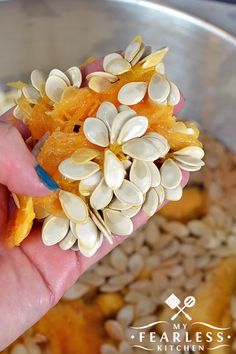 a hand holding some kind of food in it's left hand with seeds on top