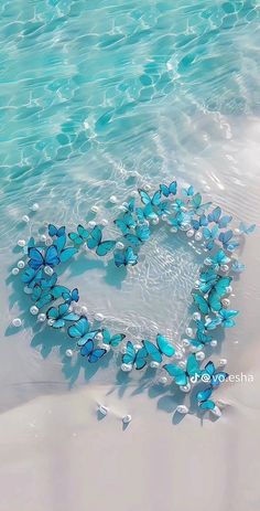 a heart made out of blue butterflies on the beach