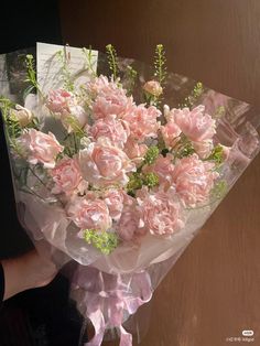 a person holding a bouquet of pink flowers