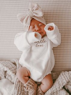 a baby laying on top of a bed wearing a white shirt and a headband