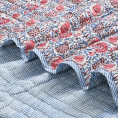 a blue and white striped quilt with red flowers on the top, along with stripes