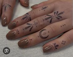 a woman's hand with tattoos on it and two fingers that have the moon and stars tattooed on them