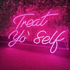 a pink neon sign that says treat or self on the side of a wall covered in flowers