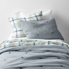 a bed with blue and yellow plaid sheets, pillows and blankets on top of it