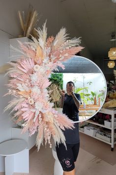 a woman is taking a selfie in front of a mirror with feathers on it