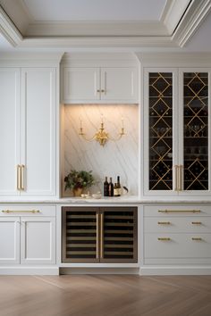 a kitchen with white cabinets and marble counter tops, gold trimmings on the doors