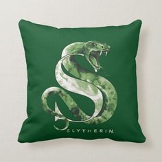 a green and white pillow with a snake on the front that says slytherin