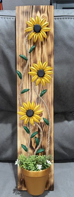 a wooden sign with sunflowers on it sitting next to a potted plant