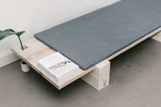 a coffee table with books and a plant on the top, sitting in front of a white wall