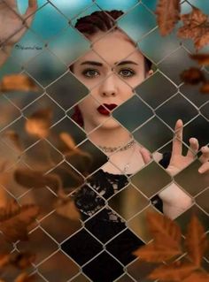 a woman behind a chain link fence with her hand up to the camera, making a weird face