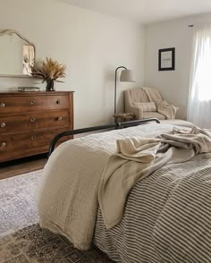 a bedroom with a bed, dresser and mirror