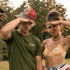 two people standing next to each other with their hands on their foreheads and one woman covering her eyes