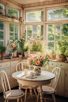 a white table and chairs in a room with flowers on the window sill above it