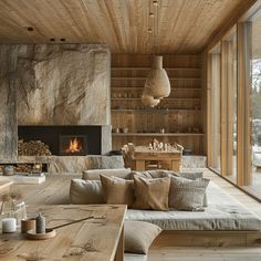 a living room filled with furniture and a fire place next to a wooden wall covered in windows