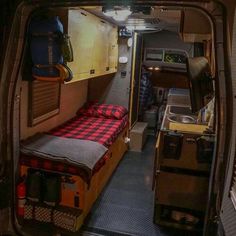 the inside of an rv with a bed, sink and stove top oven in it