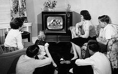 black and white photograph of people watching television