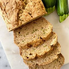 slices of zucchini bread on a cutting board next to cucumber stalks