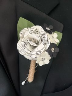 a boutonniere with paper flowers and music notes on the lapel cover