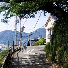 an empty road with power lines above it and mountains in the background, on a sunny day