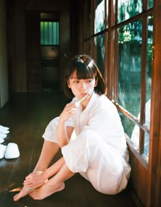 a woman sitting on the floor in front of a window