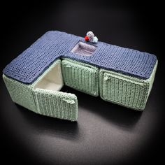 a small blue and green knitted box sitting on top of a black countertop