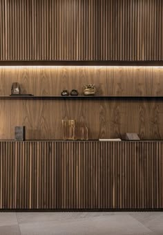 a wooden shelf with books and other items on it in front of a wood paneled wall