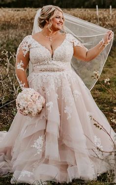 a woman in a wedding dress holding a veil over her shoulder and smiling at the camera