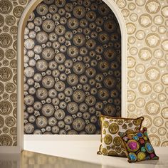 two decorative pillows sitting on top of a table next to a wall covered in circles