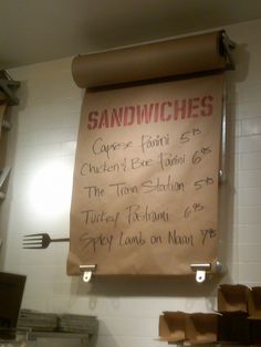 a sandwich menu hanging on the wall in a kitchen with utensils and other items