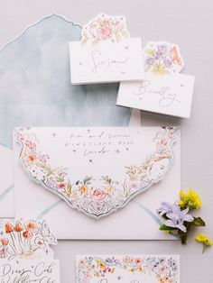 the wedding stationery is laid out on top of each other, including envelopes and cards