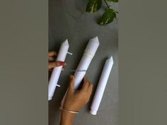 three white candles are being held by two hands