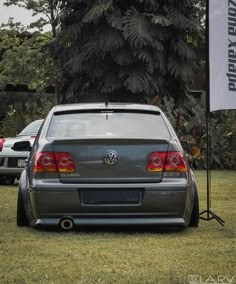 the back end of a gray car parked on top of a lush green field