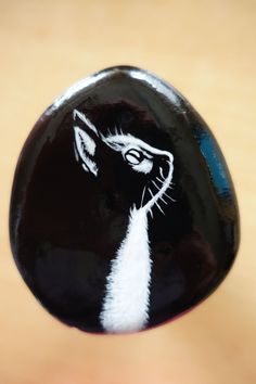 a close up of a black and white cat painted on a glass cabochon