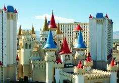 a large castle with red and blue turrets in front of a building that looks like a hotel