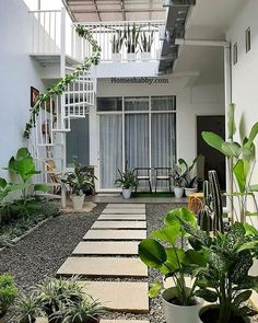 an indoor courtyard with plants and stairs leading to the second floor balcony, which also has potted plants on either side of the walkway