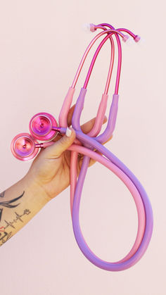 a hand holding a pair of pink and purple hair clips with scissors attached to them