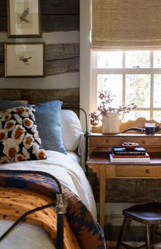 a bed sitting under a window next to a wooden desk