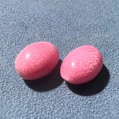 two pink eggs sitting on top of a blue carpet