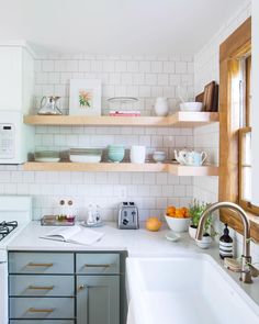 a white kitchen with open shelving above the sink