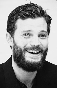 a black and white photo of a man with a goatee smiling at the camera