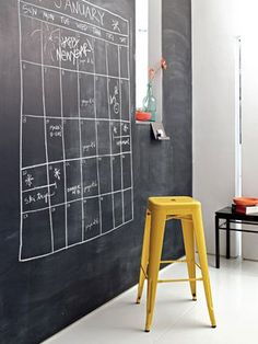 a yellow stool sitting in front of a chalkboard