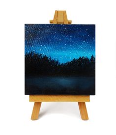 an easel with a painting on it that has a night sky in the background